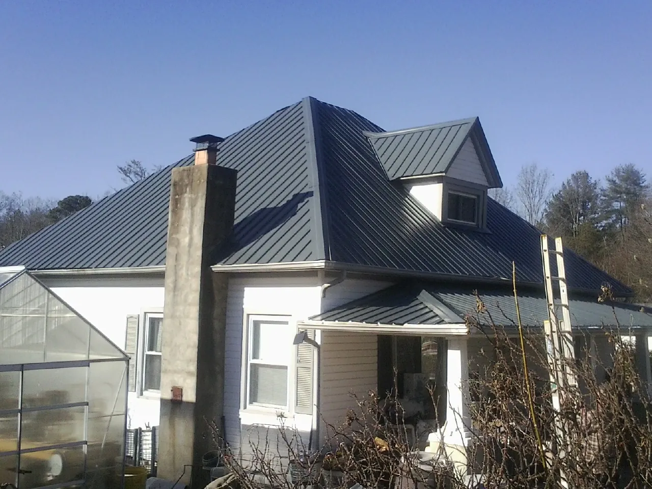 Dark blue standing seam metal roof on a white farmhouse with dormer — Slate & Tile Roof Repair by Roofing Brothers in Walnutport