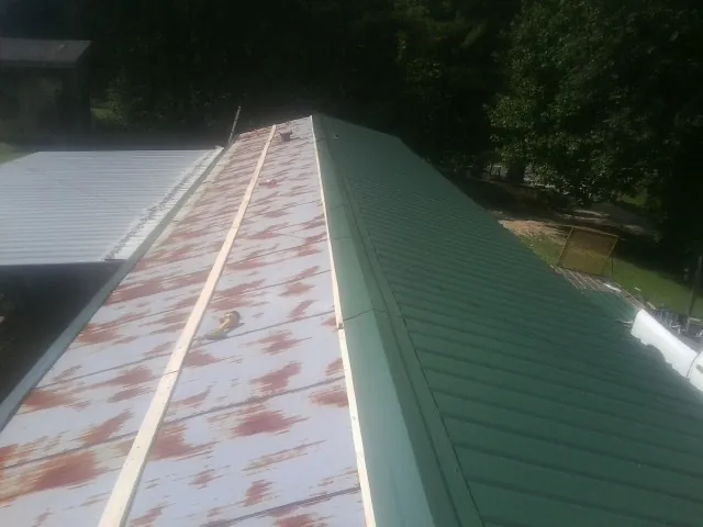 Old rusted panels beside newly installed green metal roofing — Wind Damage Roof Repair by Roofing Brothers in Walnutport