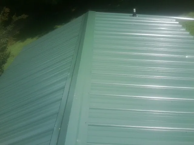 New green metal panels meeting at the ridge of a roof — Flat Roof Repair work by our crew in Walnutport