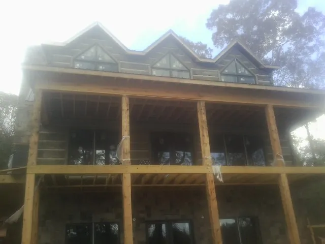 Dormers and porch framing on a large log home under construction — Roof Coating work by our crew in Walnutport