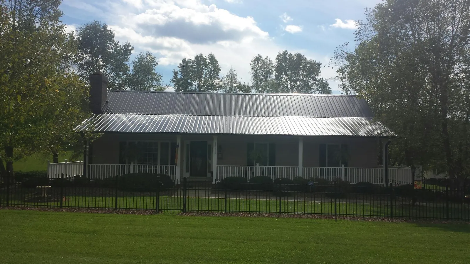 Gray metal roof on a brick ranch with a full width front porch — Gutter Guard Installation work by our crew in Walnutport