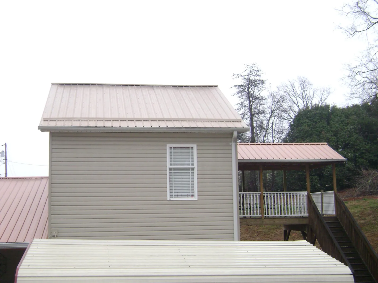 Tan metal roofs on a two story addition and attached porch, from a Roof Replacement job in Walnutport