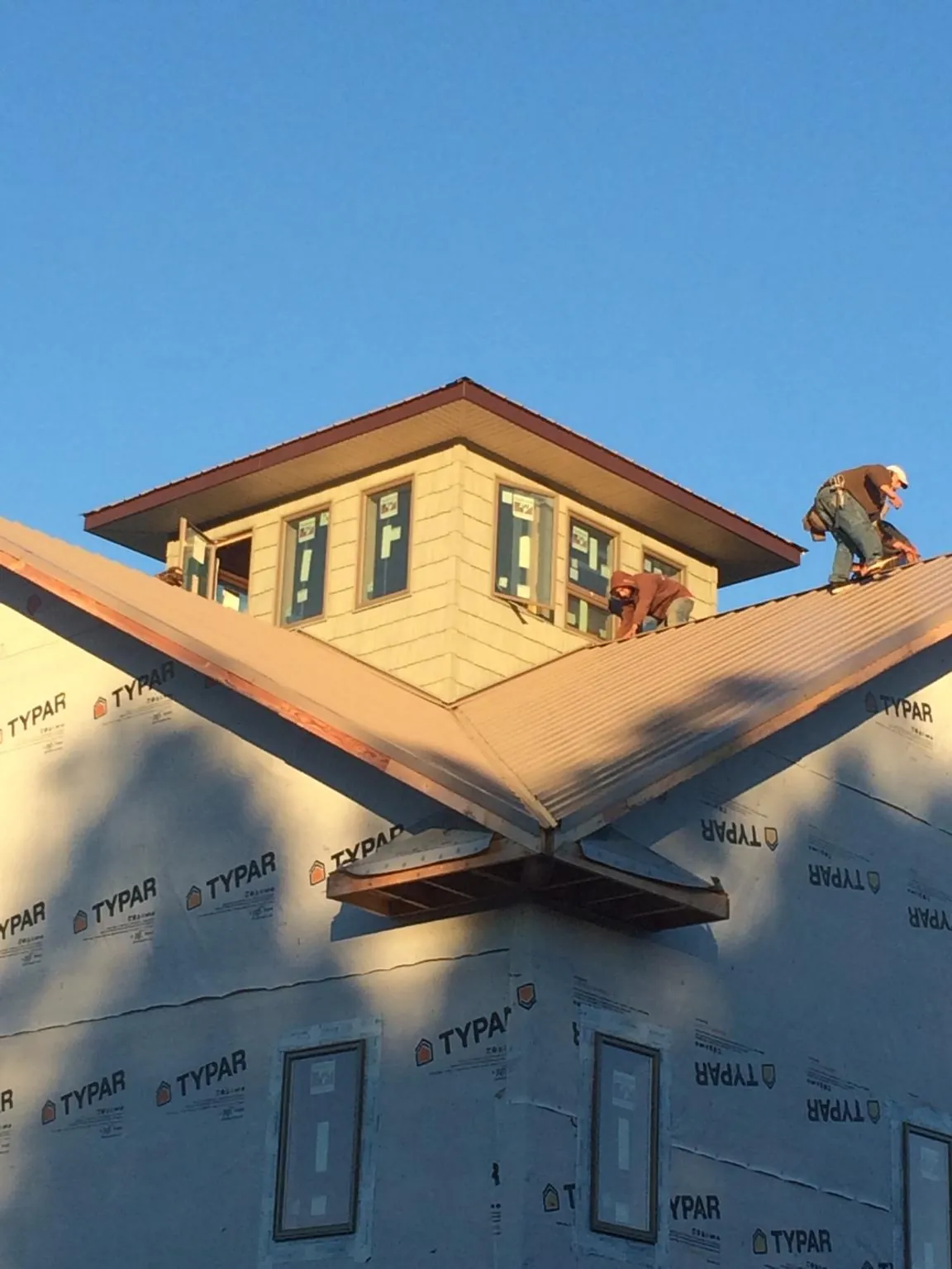Roofers working around a rooftop cupola on a new metal roof at sunset — Roof Waterproofing in Walnutport by Roofing Brothers